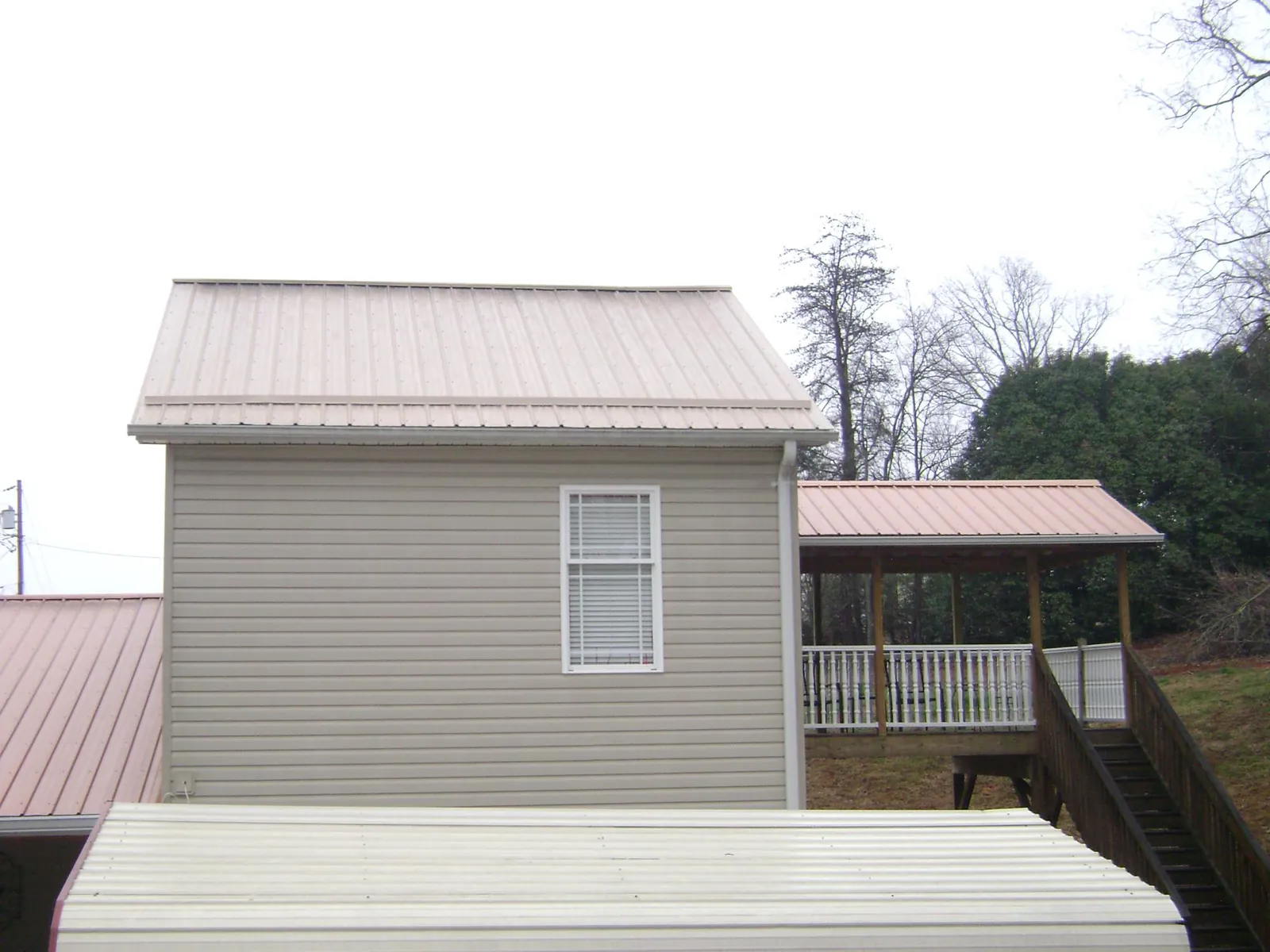 Tan metal roofs on a two story addition and attached porch, from a Roof Replacement job in Hollywood