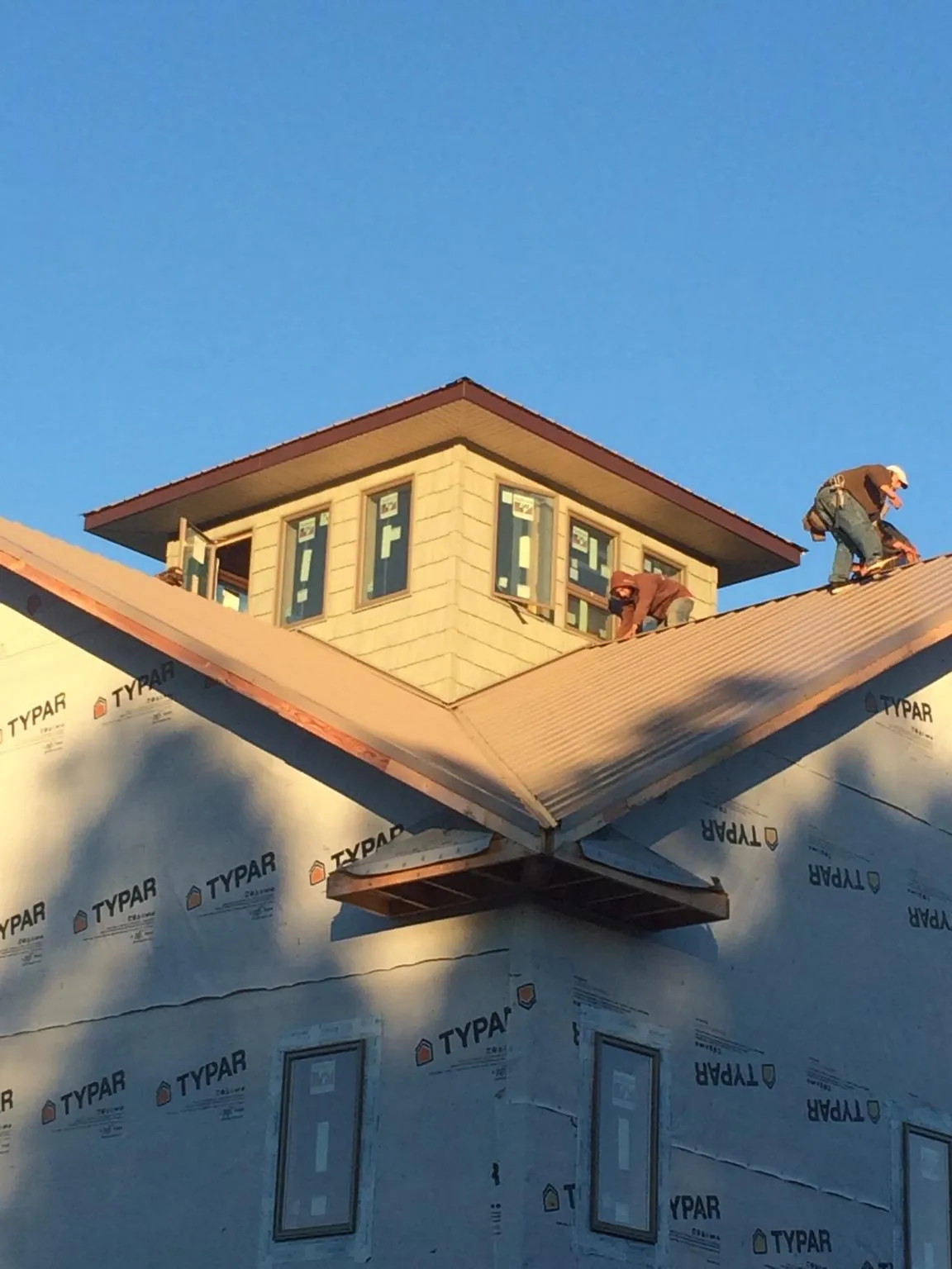 Roofers working around a rooftop cupola on a new metal roof at sunset — Roof Waterproofing in Hollywood by Roofing Brothers